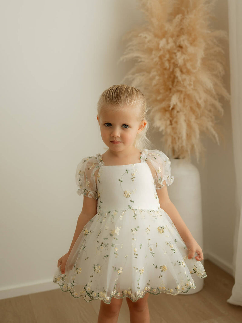 A little girl wears our yellow floral, Fleur lemon blossom baby flower girl dress.
