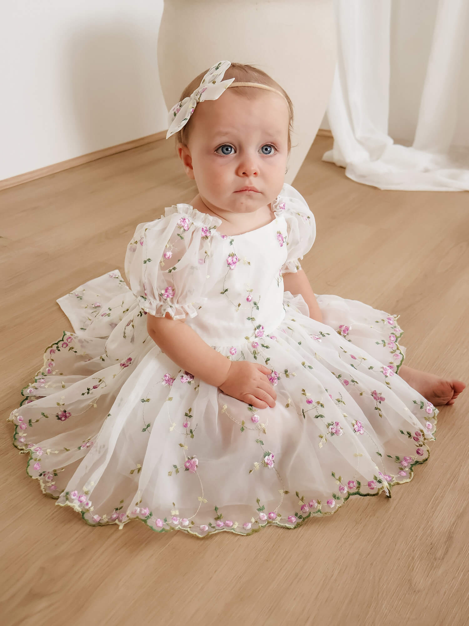 Fleur baby flower girl romper in floral embroidered organza is worn by a baby girl.