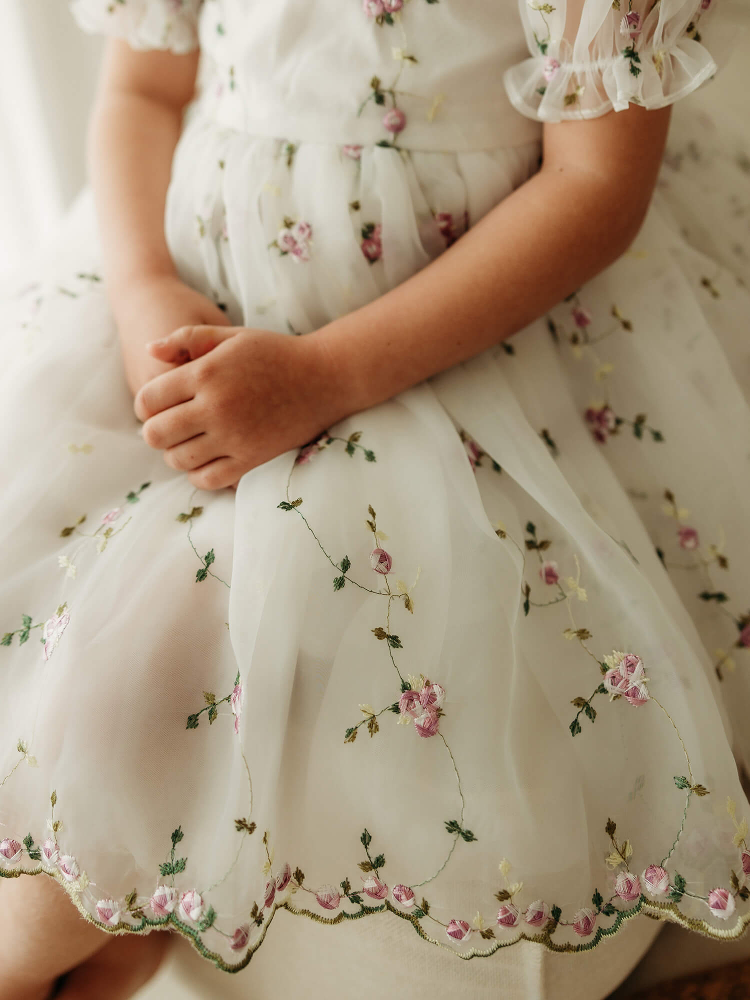 Fleur lilac flower girl dress is worn by a young girl, showing the embroidered floral details on the hem.