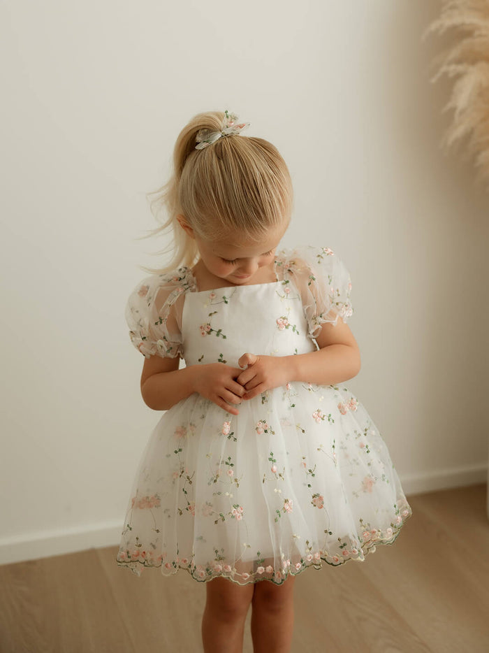 Fleur pink floral organza baby flower girl romper is worn by a young girl.