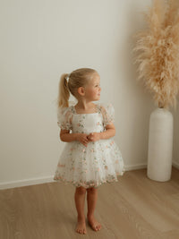 A little girl wears our Fleur baby flower girl romper dress, with puff sleeves.