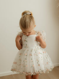 A young girl wears our Fleur toddler flower girl dress, made in pink embroidered floral organza.