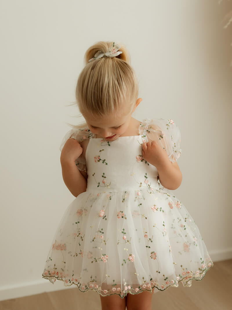 A young girl wears our Fleur toddler flower girl dress, made in pink embroidered floral organza.