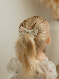Fleur meadow pink embroidered organza bow hair clip is worn by a young girl.