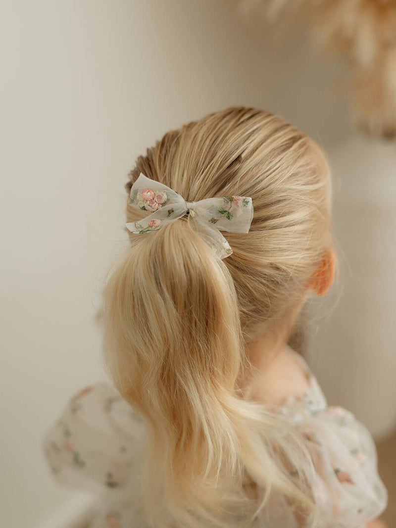 Fleur meadow pink embroidered organza bow hair clip is worn by a young girl.