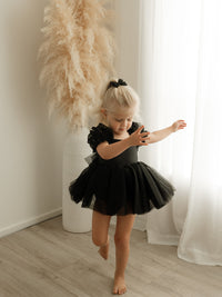 A toddler twirls wearing our Gabrielle black flower girl dress for babies and toddlers.