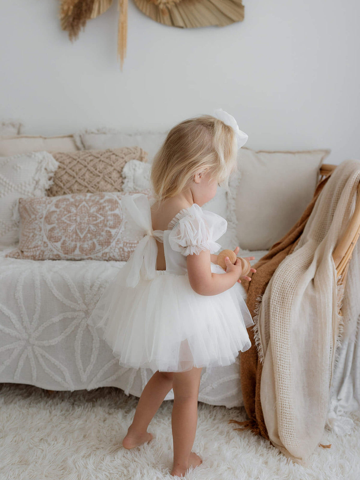 Toddler wears our cream Gabrielle baby flower girl outfit with tulle bow back.