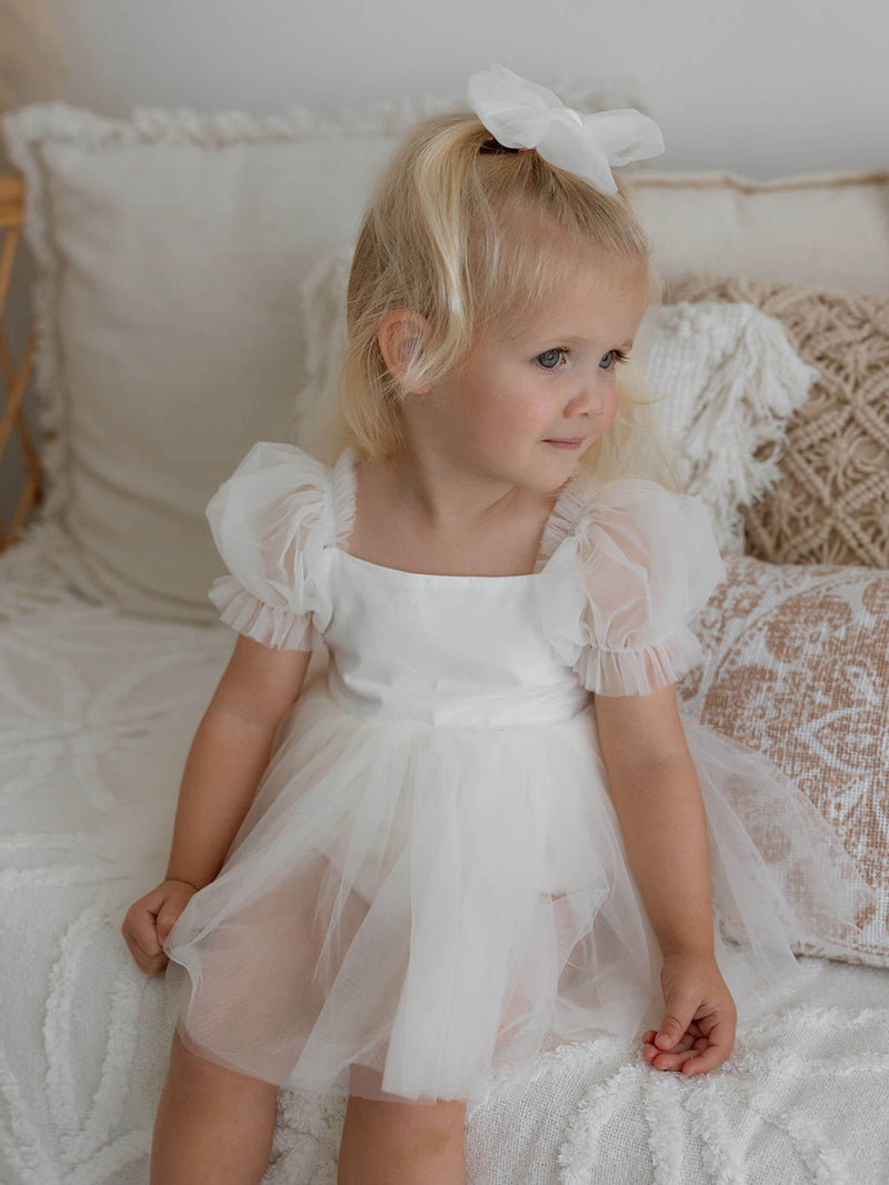 Young girl in our Gabrielle cream flower girl romper dress with tulle sleeves.