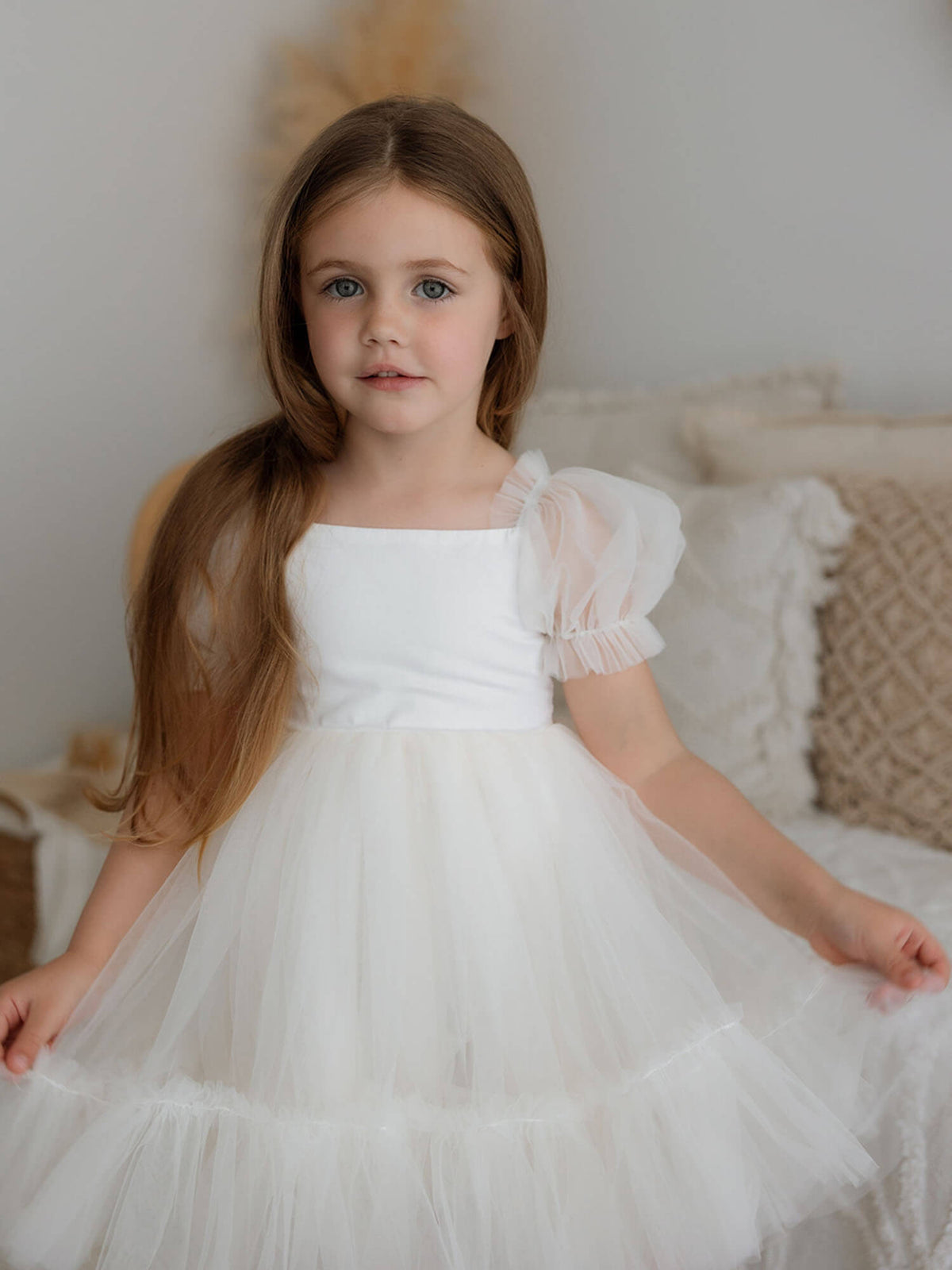 Our Gabrielle cream tulle flower girl dress is worn by a young girl.