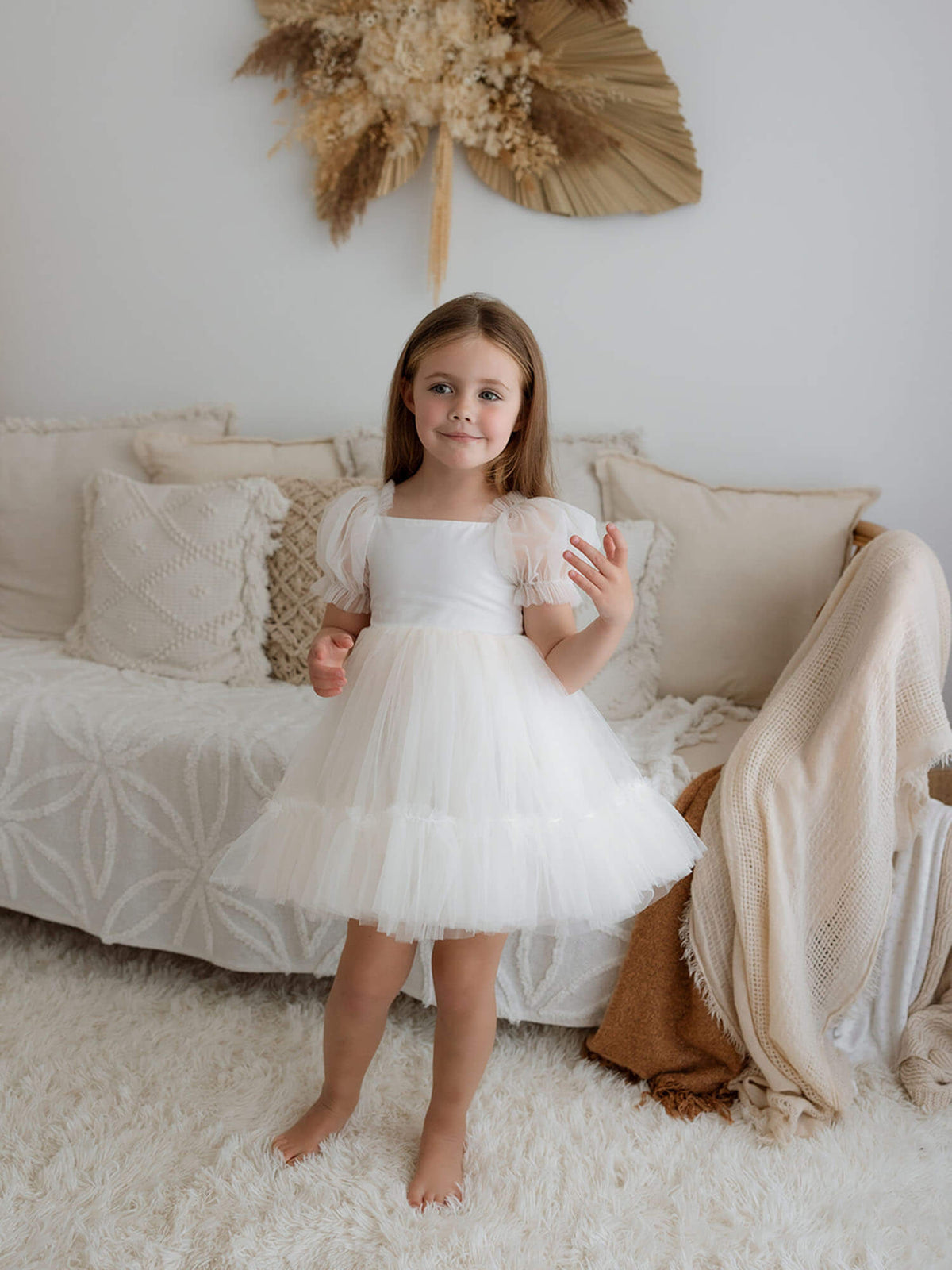 Gabrielle cream tulle flower girl dress is worn by a little girl.