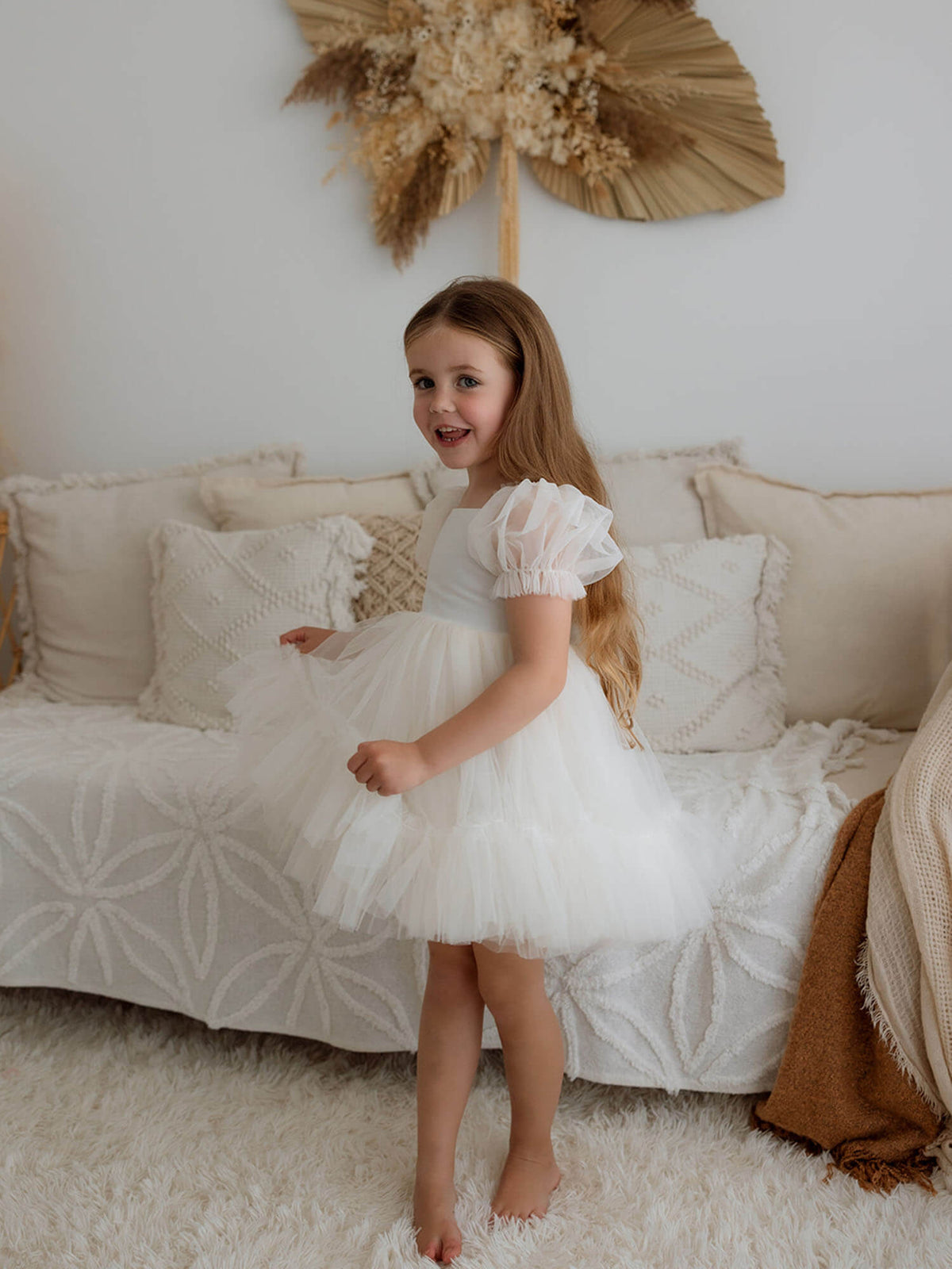 A little girl twirls wearing our Gabrielle tulle flower girl dress in cream.