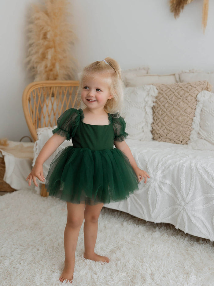 A toddler wears our Gabrielle flower girl romper in emerald green.