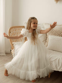 A little girl dances wearing our Gabrielle ivory tulle flower girl dress in full length.