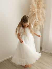 Gabrielle full length ivory flower girl dress is worn by a young girl who is twirling the skirt.