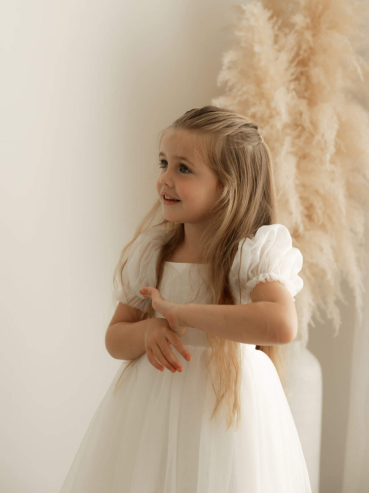 Showing the tulle puff sleeves on the ivory full length flower girl dress.