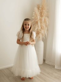 Gabrielle ivory tulle full length flower girl dress is worn by a smiling little girl.