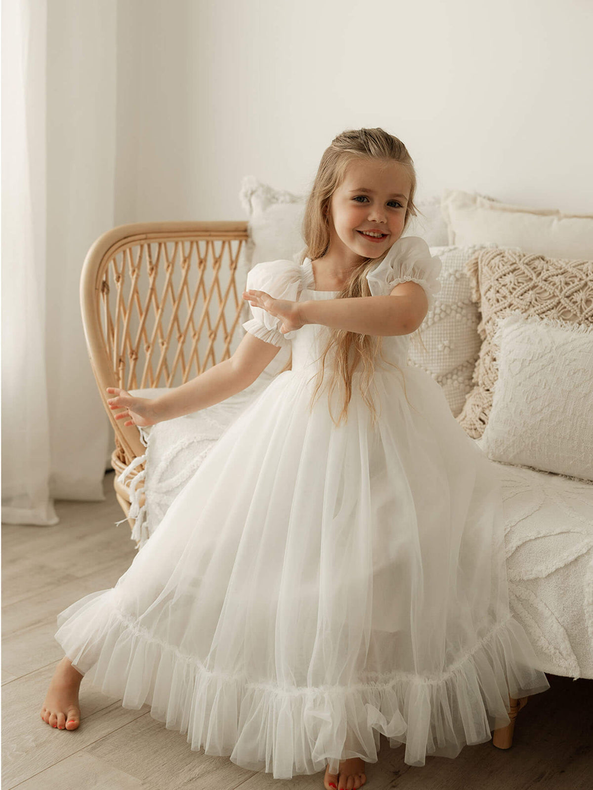 A young girl wears our Gabrielle full length tulle flower girl dress in ivory.