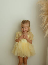Lemon yellow baby flower girl romper is worn by a young girl.