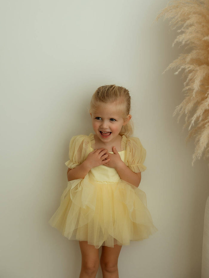 Lemon yellow baby flower girl romper is worn by a young girl.
