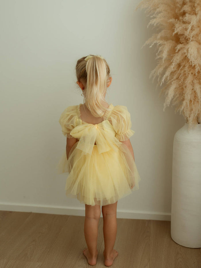 The back of our lemon yellow Gabrielle flower girl romper, with lemon tulle back bow.