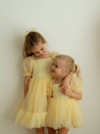 Sisters wearing matching lemon yellow flower girl dresses.