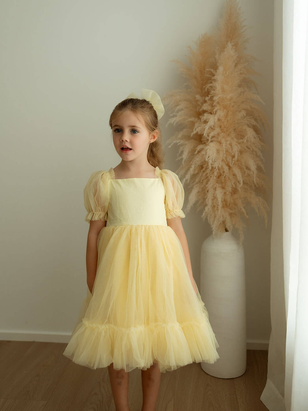 Gabrielle lemon yellow flower girl dress is worn by a little girl.