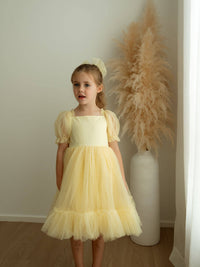 Gabrielle lemon yellow flower girl dress is worn by a little girl.