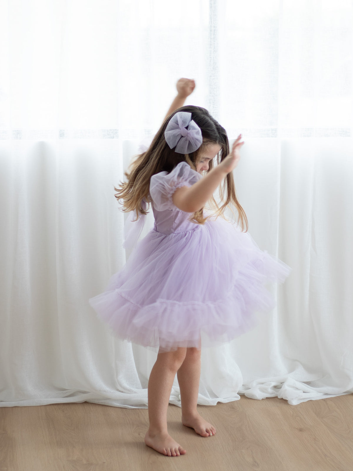 A little girl twirls wearing our Gabrielle lilac purple flower girl dress.