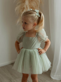 Gabrielle sage green baby flower girl dress is worn by a toddler.