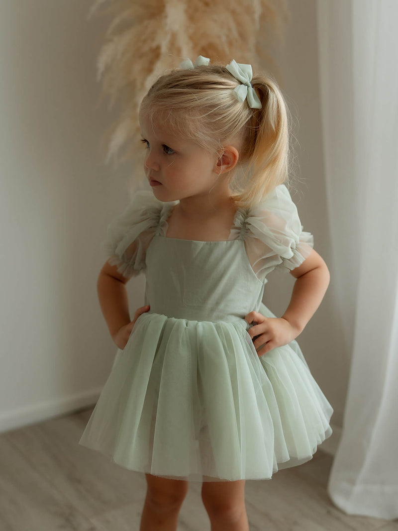 Gabrielle sage green baby flower girl dress is worn by a toddler.