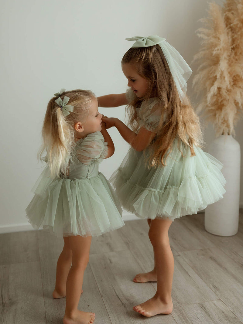 Sisters dance wearing matching Gabrielle sage green flower girl outfits.