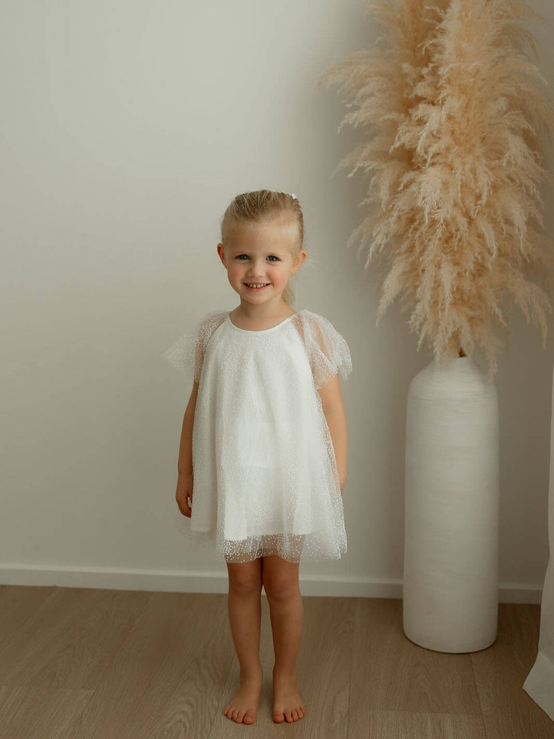 Child wears our Gia ivory flower girl romper.