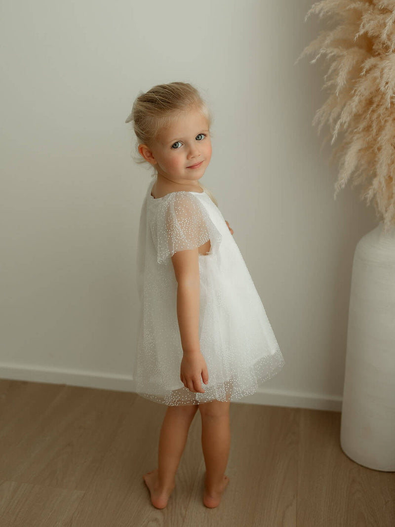 Gia ivory baby flower girl romper is worn by a young girl.