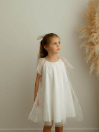 Gia confetti tulle flower girl dress is worn by a young girl.