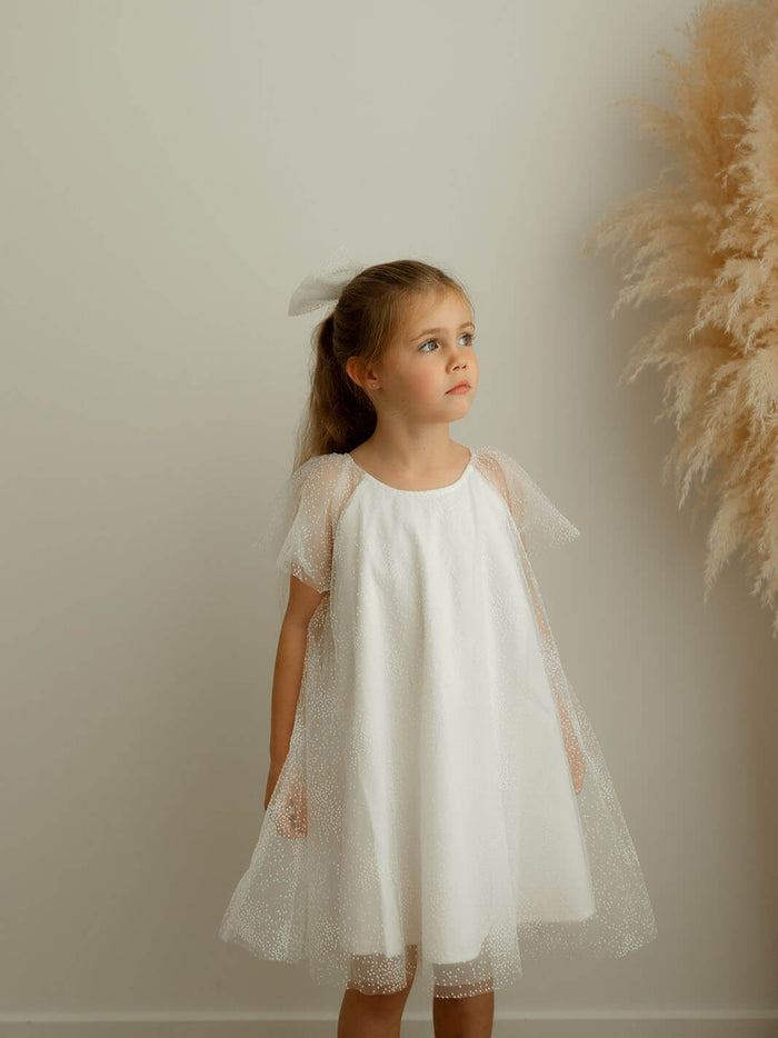 Gia confetti tulle flower girl dress is worn by a young girl.
