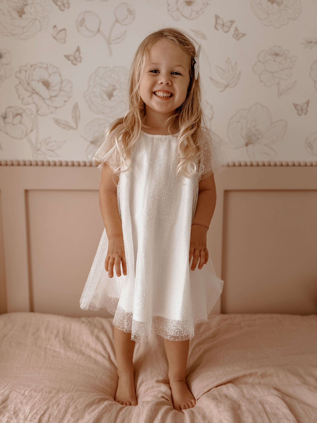 Gia flower girl dress in flocked dot tulle is worn by a young girl who is smiling.