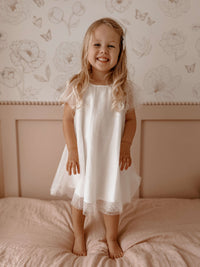 Gia flower girl dress in flocked dot tulle is worn by a young girl who is smiling.
