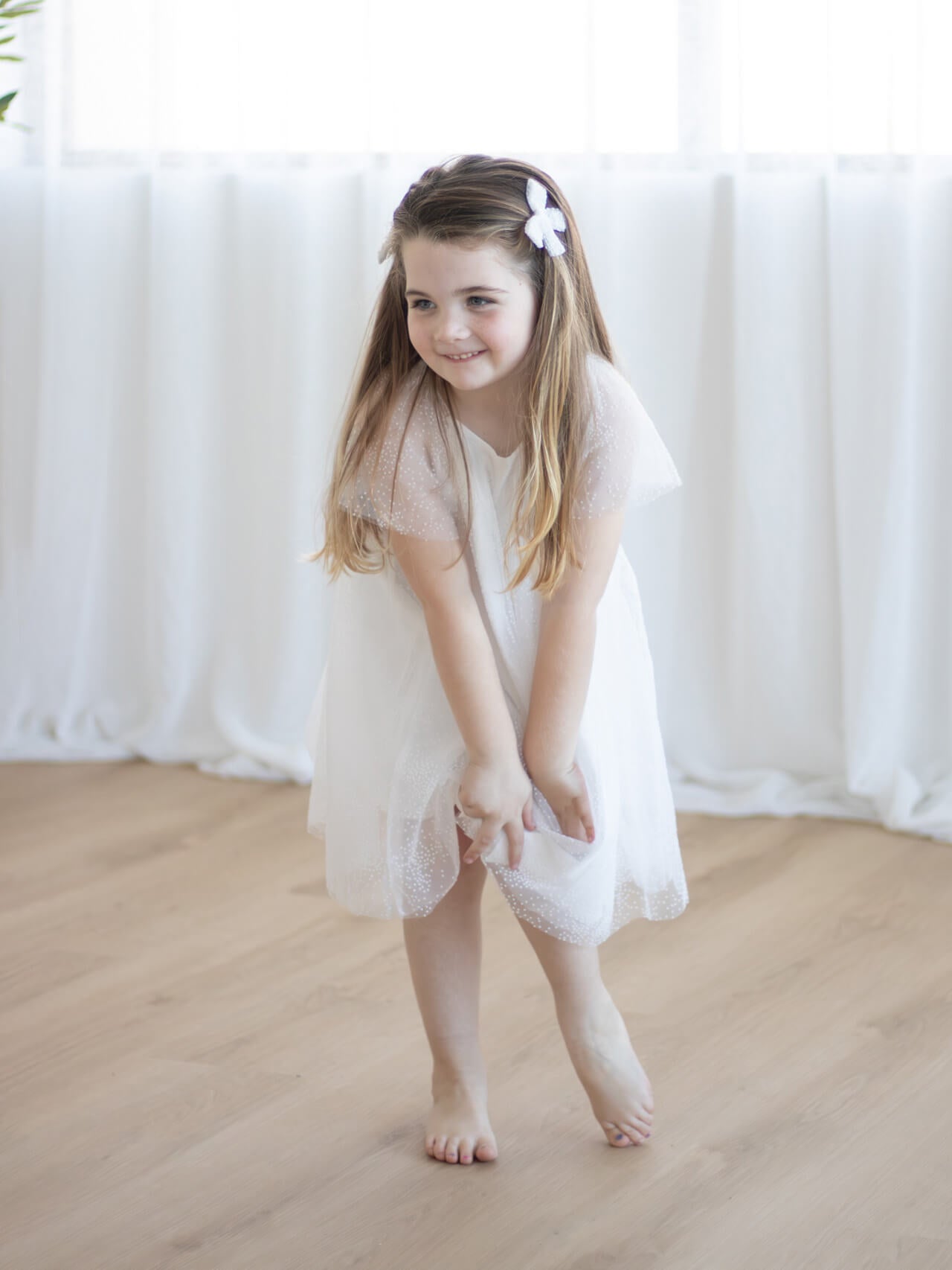 A little girl wears our Gia flower girl dress with matching pigtail bows.