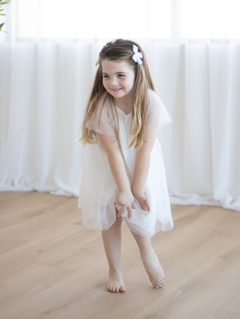 A little girl wears our Gia flower girl dress with matching pigtail bows.
