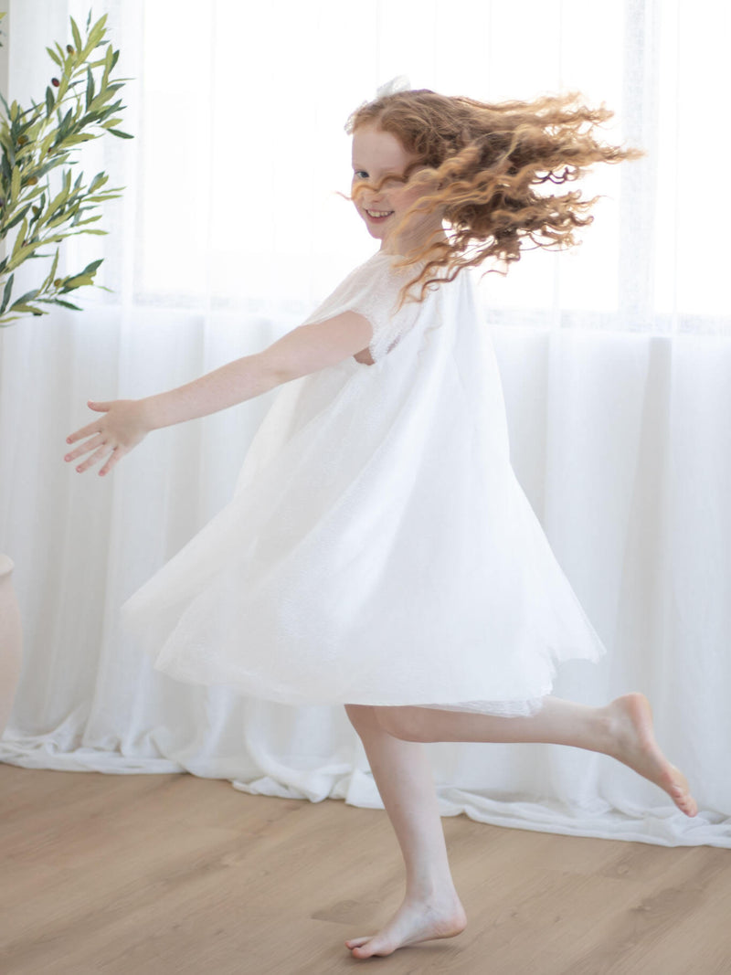 Gia flower girl dress is worn by a young girl, who is twirling.