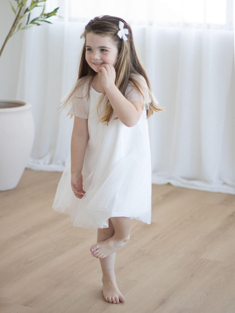 Gia flower girl dress and matching flocked confetti tulle bows are worn by a young girl.