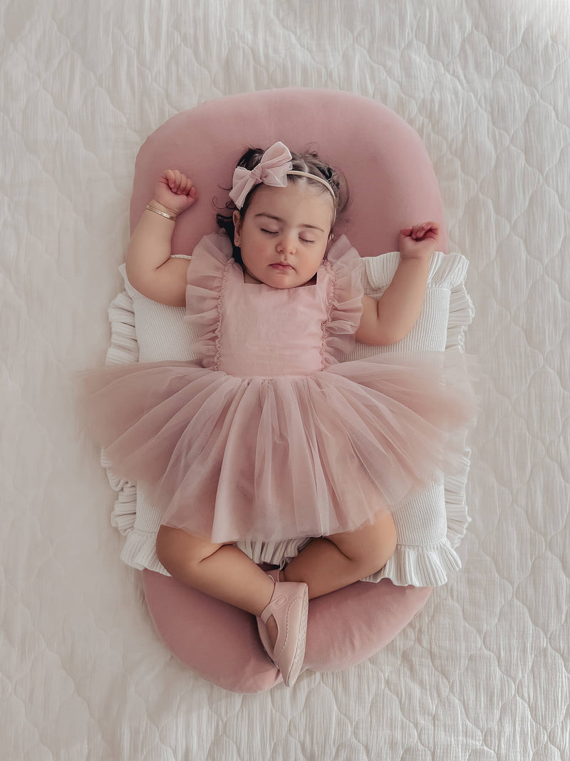Gigi baby flower girl dress in dusty pink is worn by a baby girl.