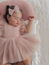 Gigi baby flower girl outfit is worn by a sleeping baby. She also wears our dusty pink tulle bow headband.