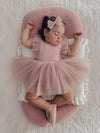 Baby girl sleeps wearing Gigi dusty pink baby flower girl dress and tulle bow headband.