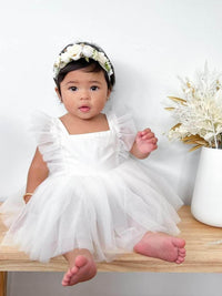Gigi ivory tulle baby flower girl romper is worn by a baby.