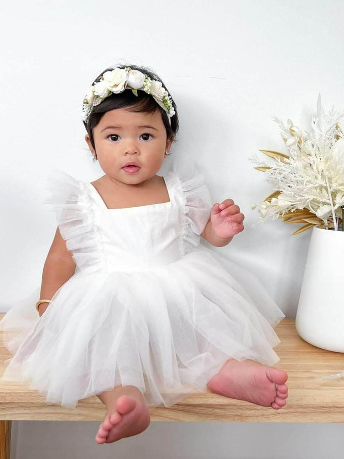 Gigi ivory tulle baby flower girl romper is worn by a baby.