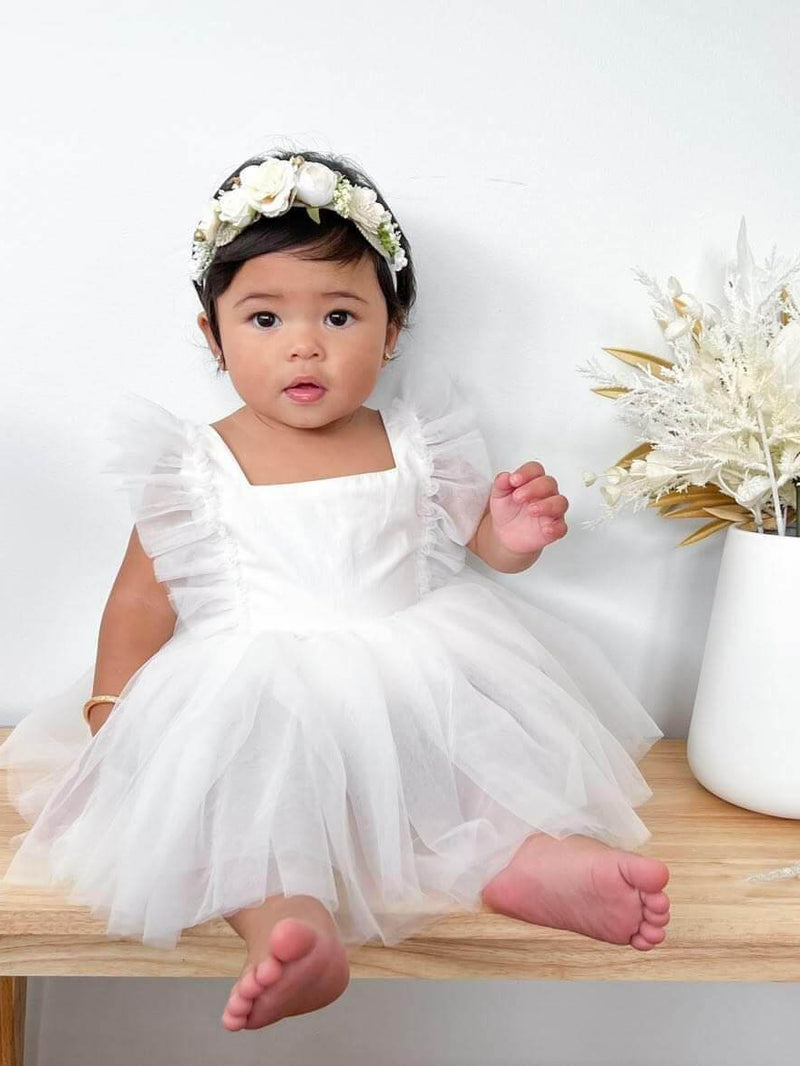 Gigi ivory tulle baby flower girl romper is worn by a baby.