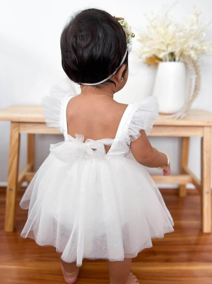 A baby wears our Gigi baby flower girl romper, showing the tulle bow at the back.