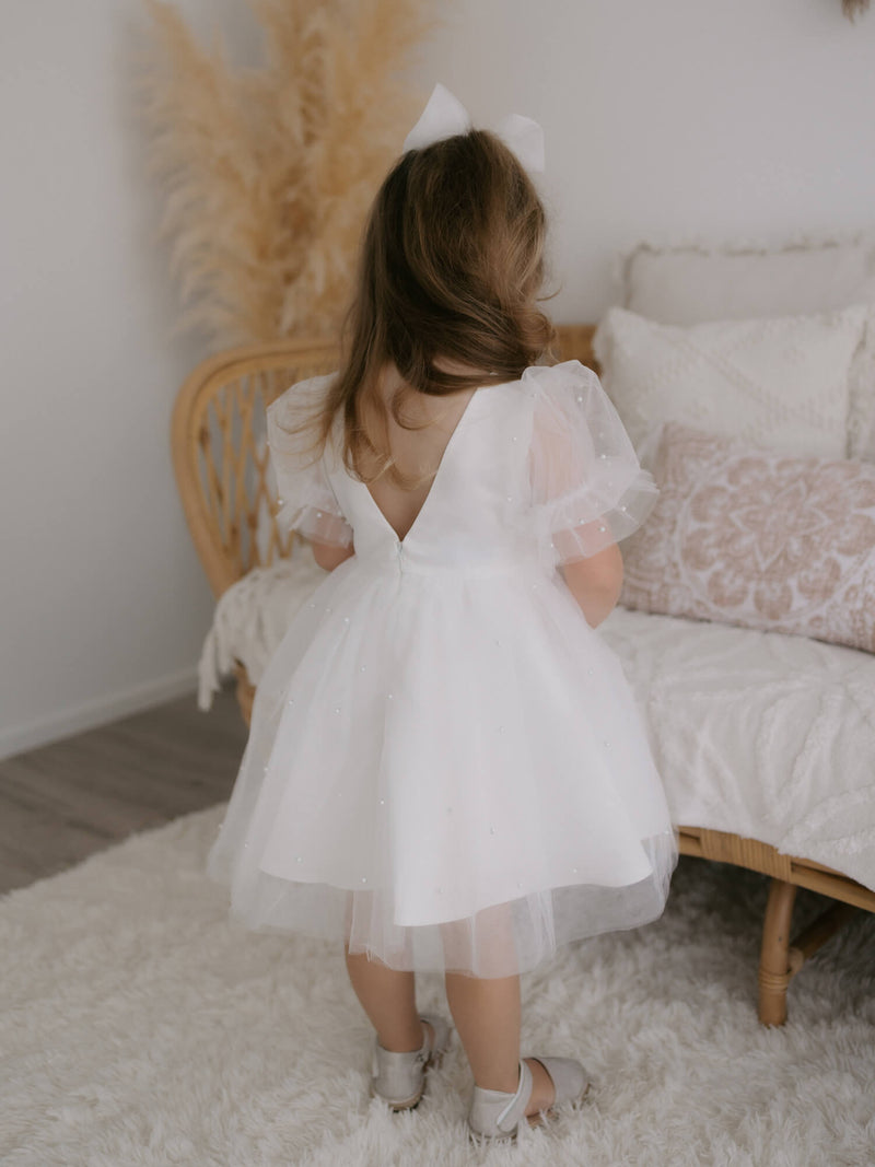 The back of our Gracie puff sleeve flower girl dress, worn by a young flower girl.