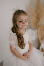 Gracie beaded puff sleeve flower girl dress is worn by a young girl.